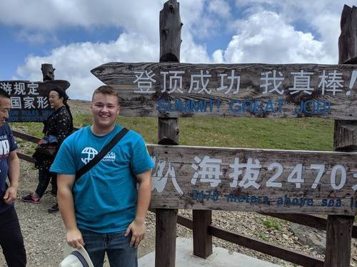 Alumnus Eric Brink in front of a sign written in Chinese